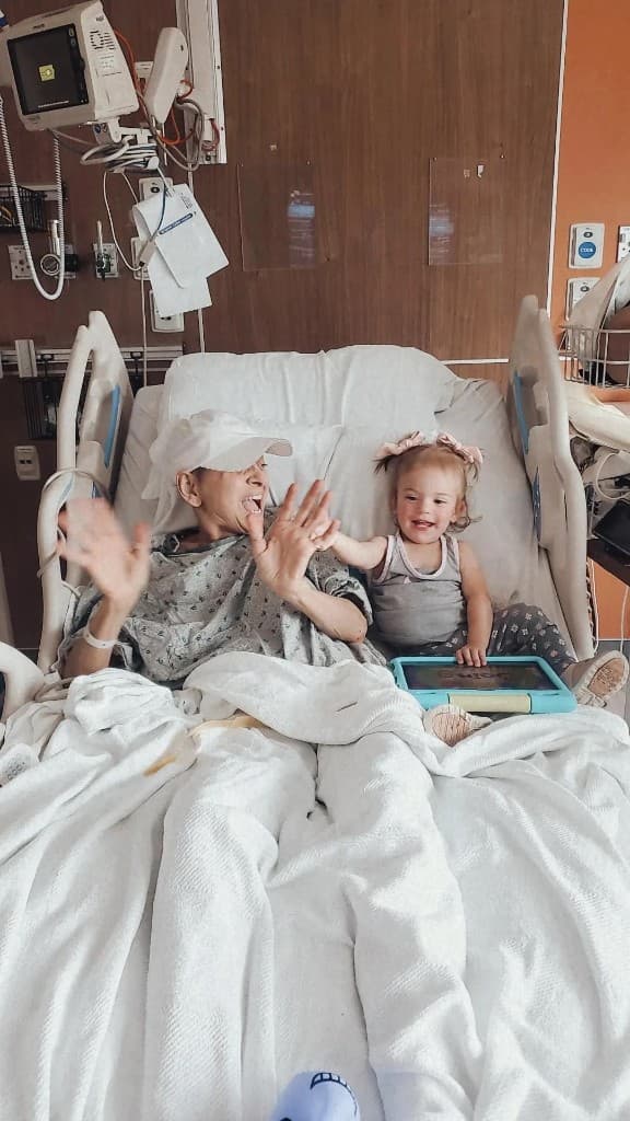 A patient in a hospital bed with a young child.