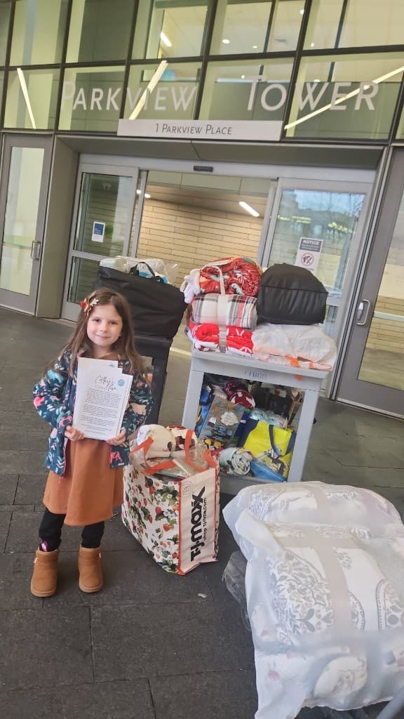 A child with blankets outside a hospital entrance.